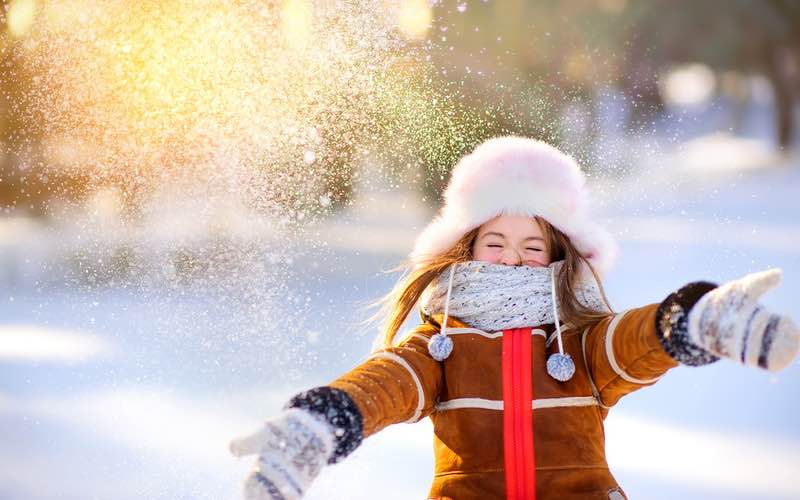 Little girl playing in the snow during the holiday season - contact Romp n' Roll for holiday learning in Katy, TX!