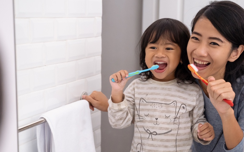 Mother teaching child a new routine of brushing her teeth, learned from Romp n' Roll.