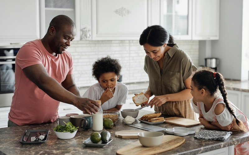 Parents and two children helping prepare a meal together in the kitchen.