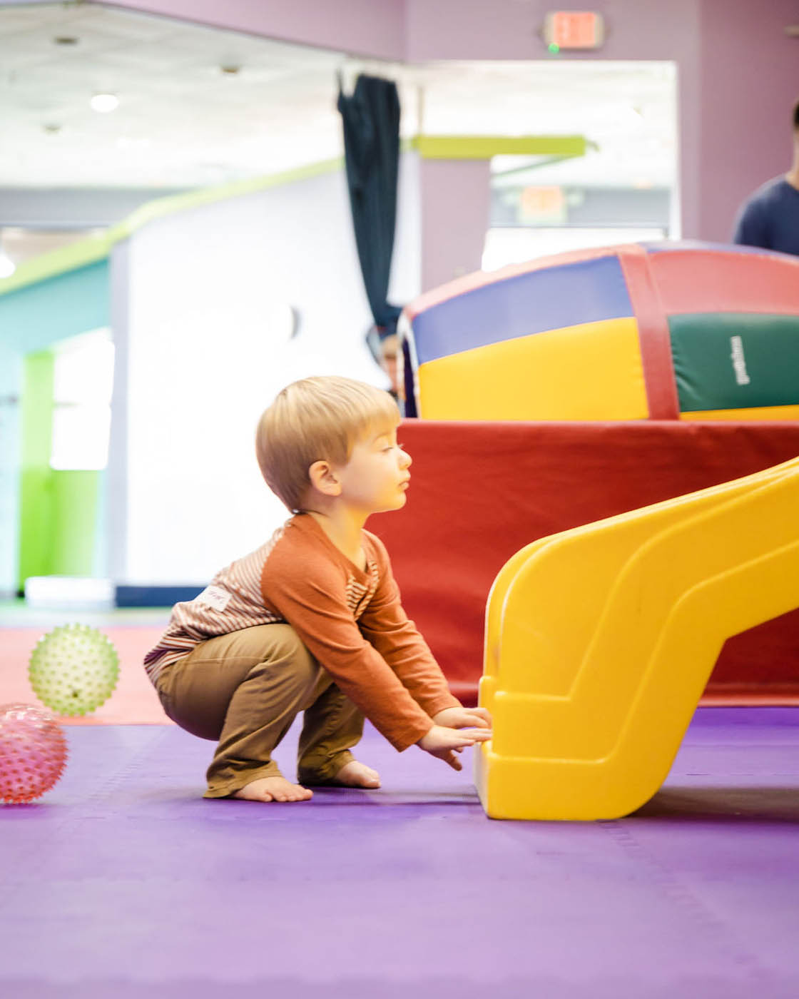 A kid on a yellow slide at Romp n' Roll - explore our membership options.