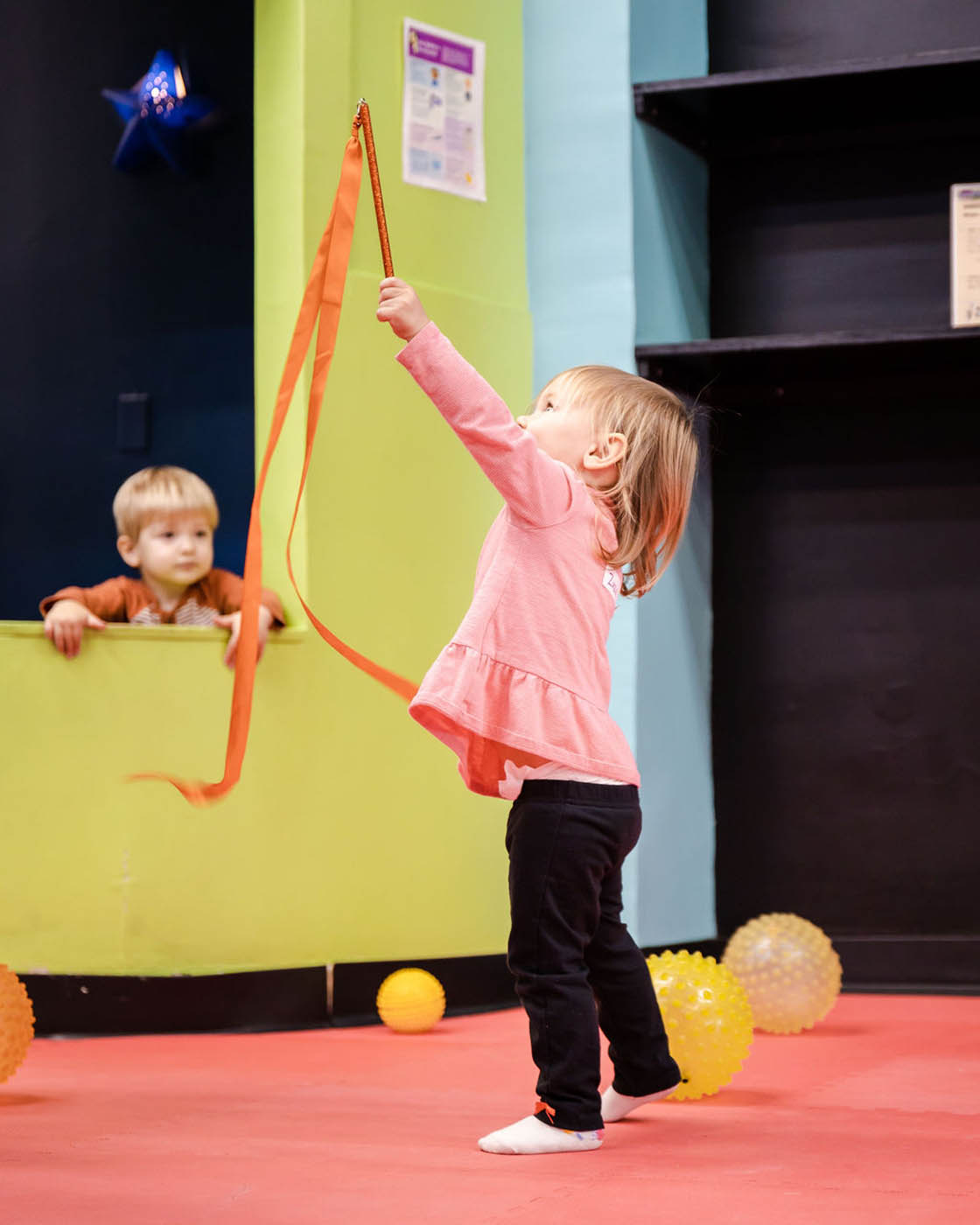 A girl playing with ribbons - experiencing the color and joy of movement at Romp n' Roll in Katy.