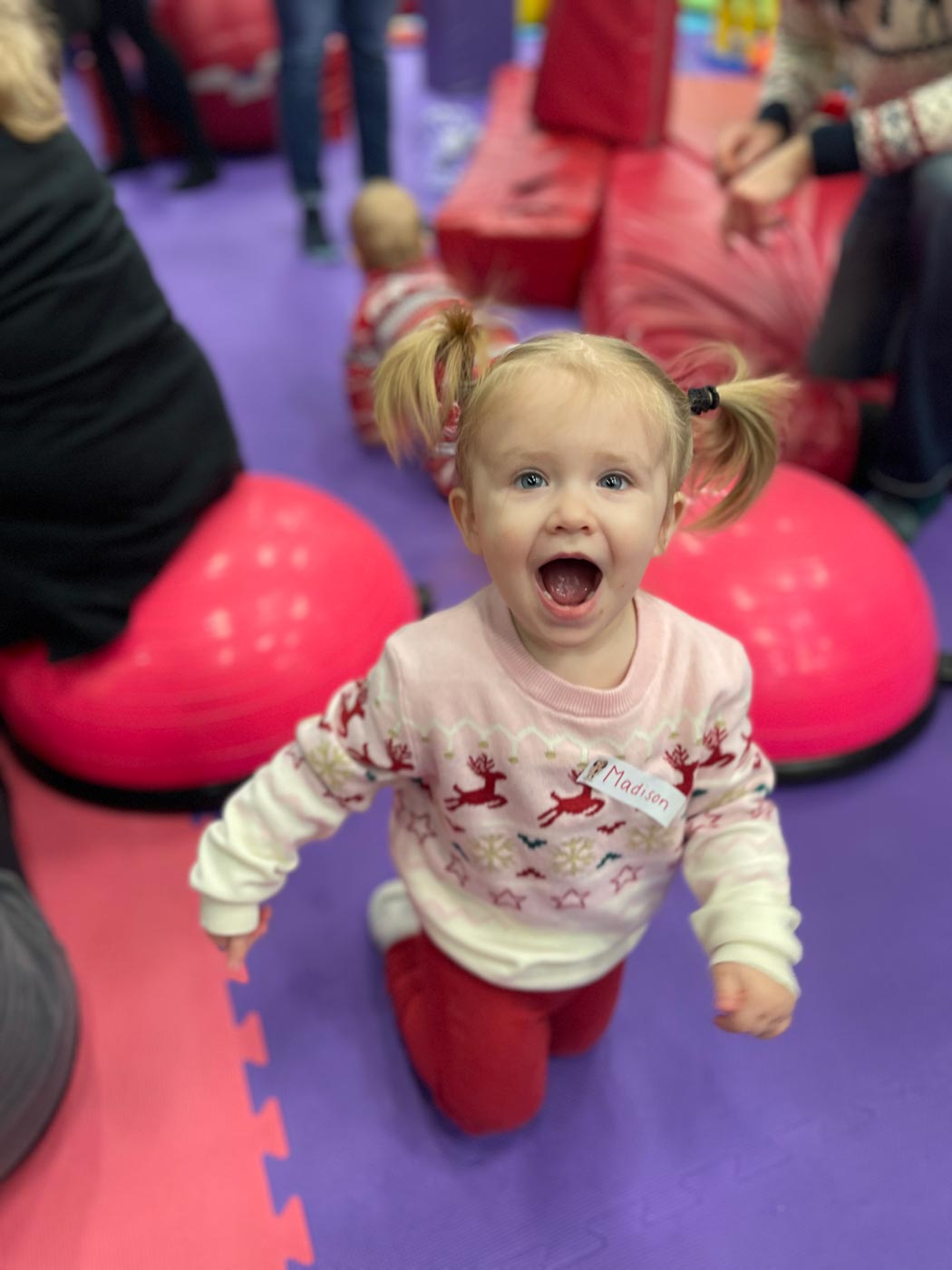 A little girl on a purple matt, having fun at Romp n' Roll's winter camp in Katy, TX. 