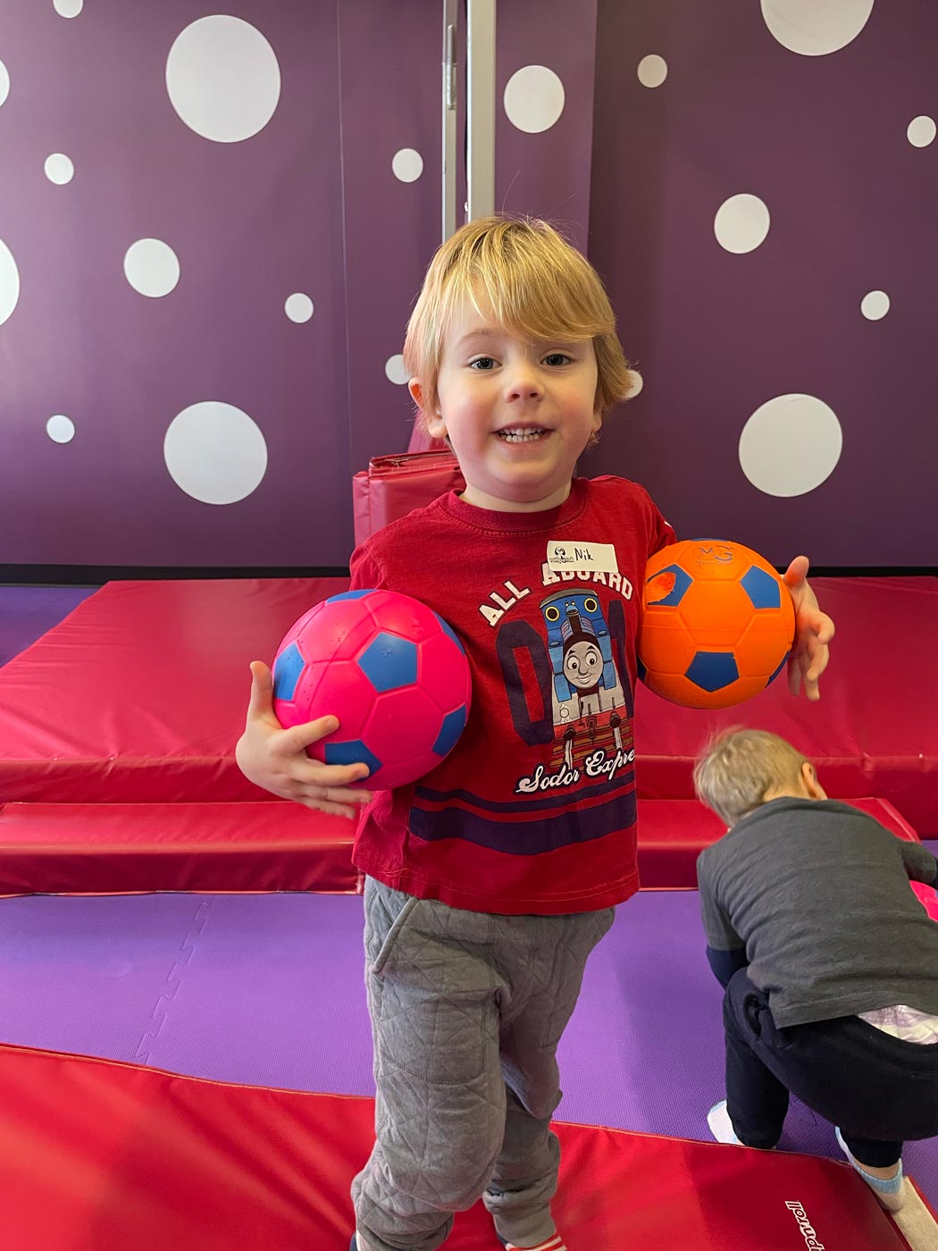 A little boy playing with soccer balls in Romp n' Roll Wethersfield's gym.