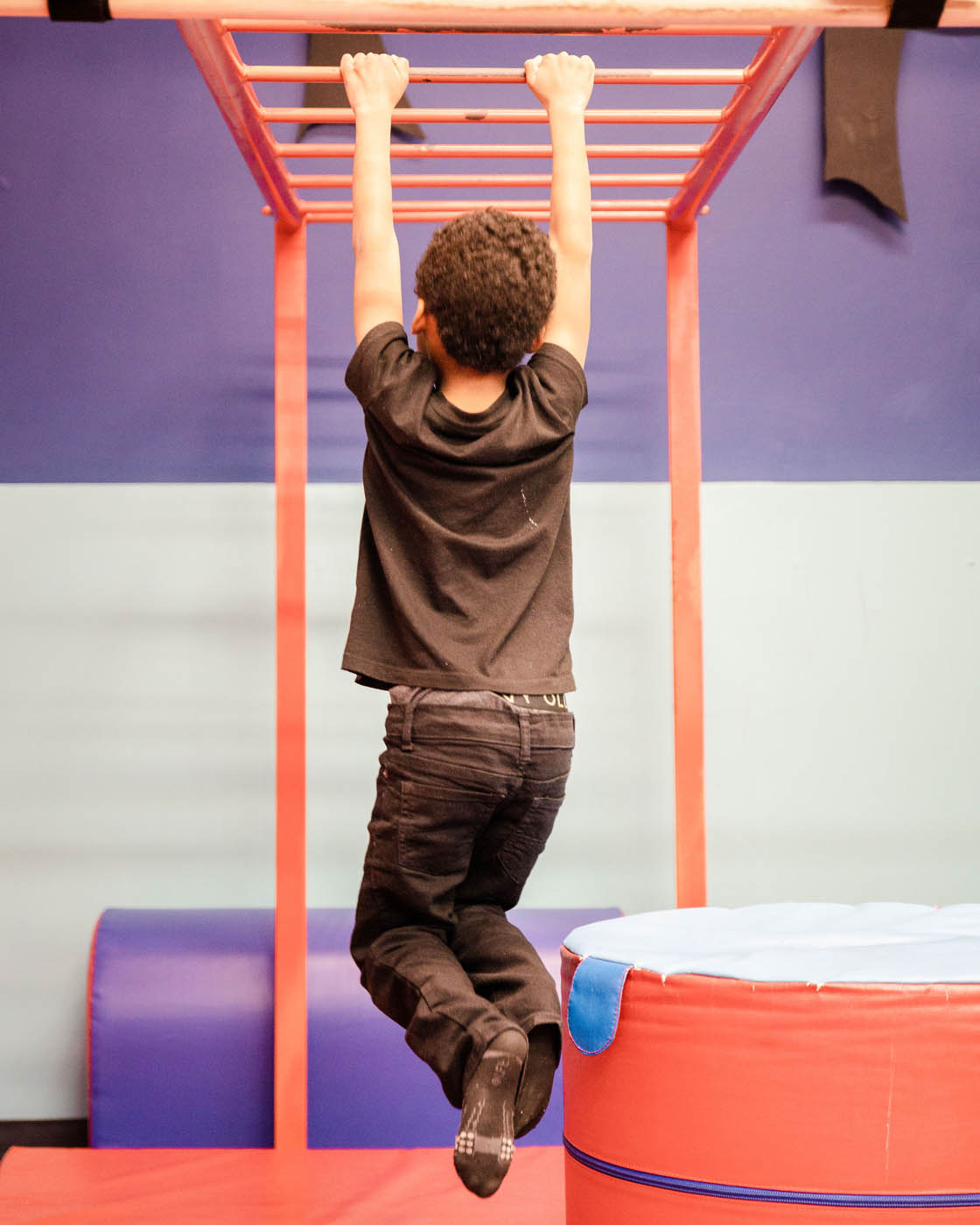 A little boy hanging on monkey bars, contact us today about our baby groups in Katy, TX.