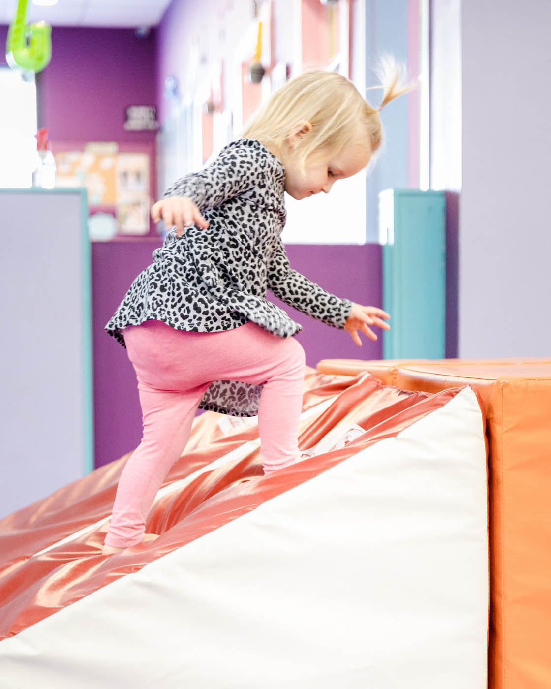 A girl climbing on soft gym equipment for gymnastics for 2 year olds in Katy, TX.