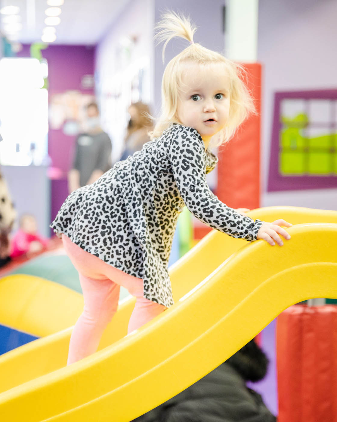 A little girl climbing up a yellow slide at Romp n' Roll in Midlothian, VA.