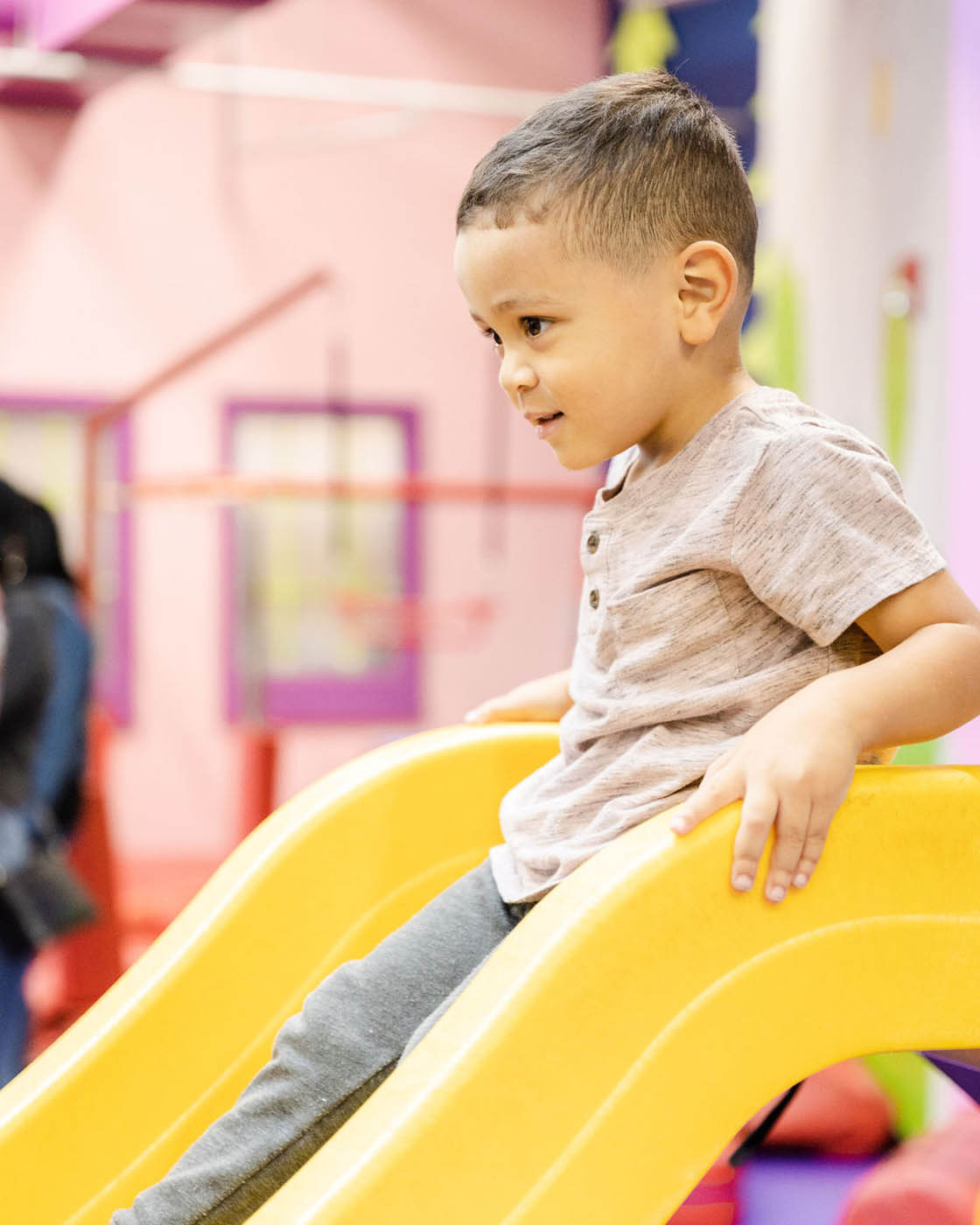 A little boy playing on a yellow slide at Wethersfield's winter camps for kids.