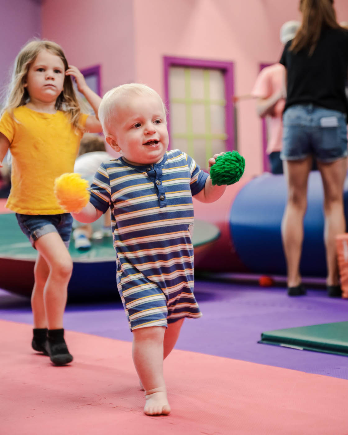 A boy holding some fluffy toy balls at Romp n' Roll in Raleigh.