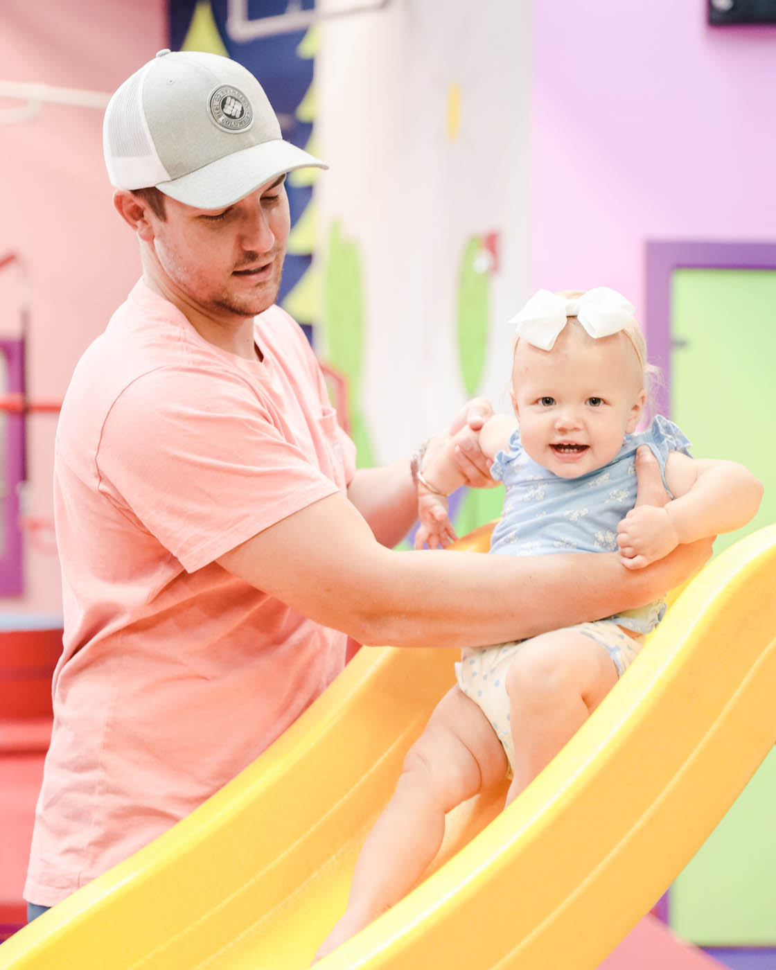 A young baby girl going down the slide at enrichment classes for kids in Glen Allen, VA at Romp n' Roll.