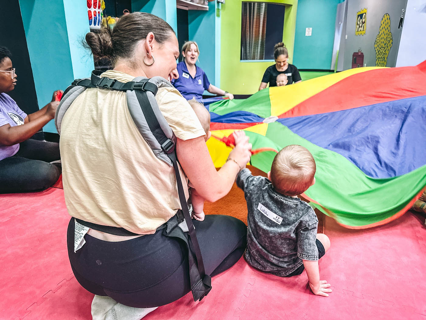 A parent and child playing with a parchute at Romp n' Roll, learn more about to do with things to do with kids in Katy, TX.