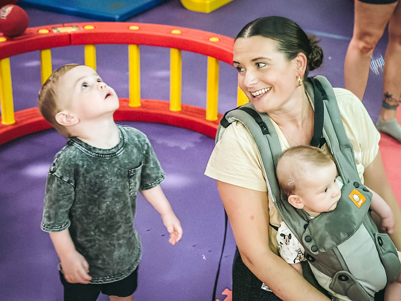 An adult holding a baby and a younger boy standing next to her - join our preschool classes in Glen Allen, VA today.