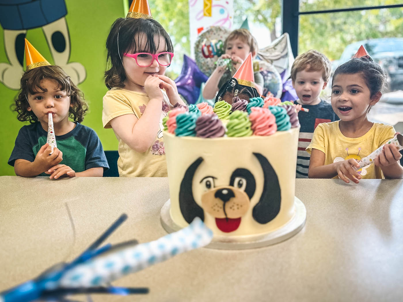 A young girl celebrating her birthday with friends and a Rompy cake at Romp n' Roll toddler birthday venues in Katy, TX.