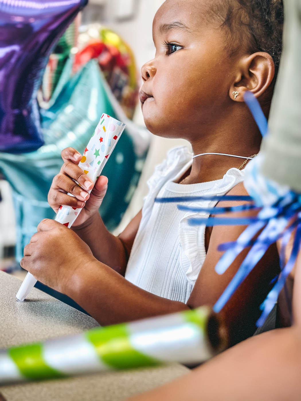 A little girl playing with some wrapping paper, book a birthday party in Midlothian, VA today!