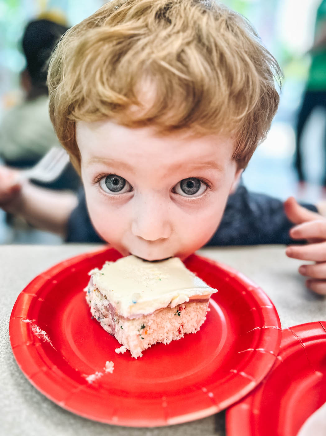 A kid taking a big bite out of a cake piece at Romp n' Roll - a children's party place in Katy, TX.