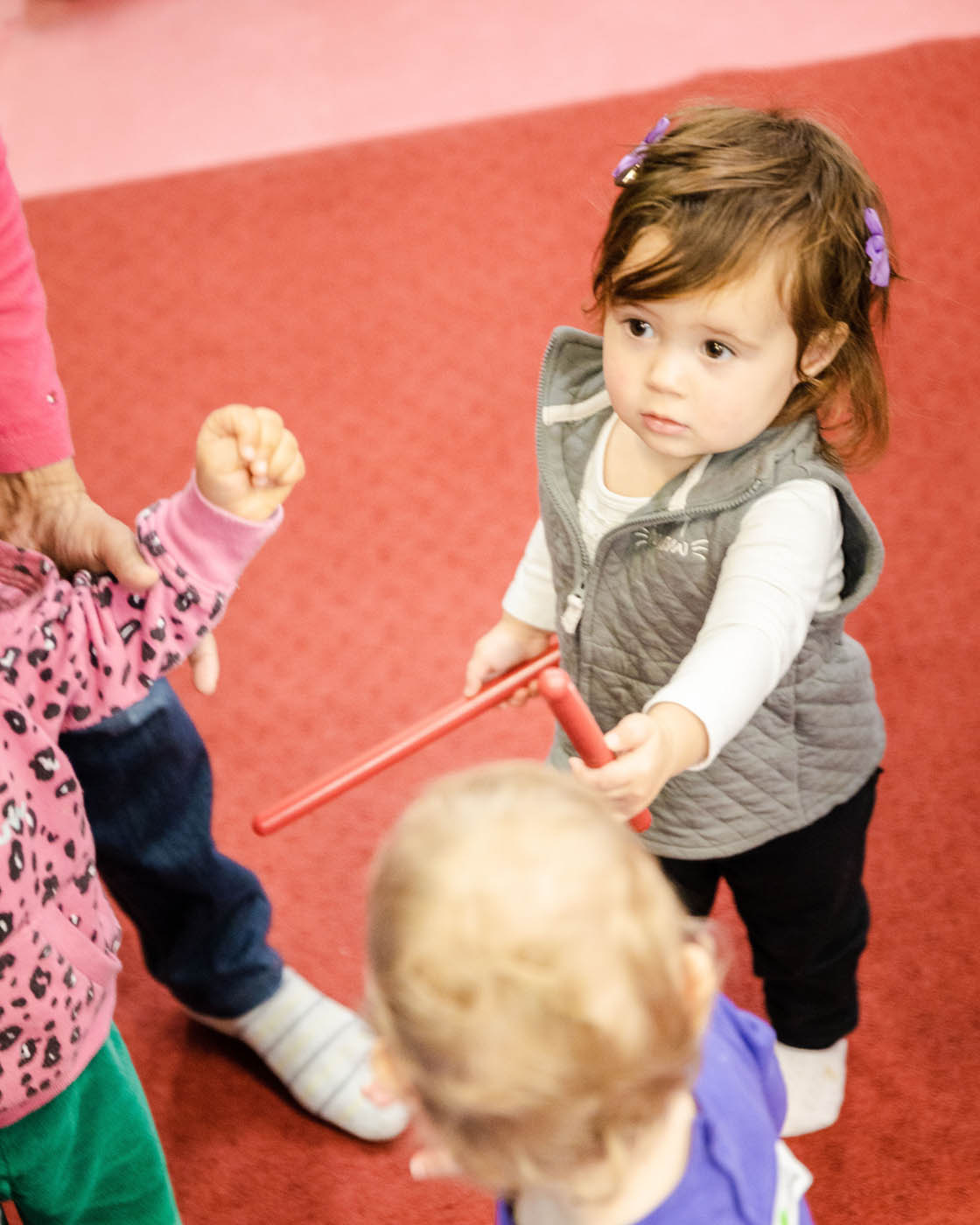 A little girl playing with music instruments at Romp n' Roll Katy's kids night out event in Katy, TX.