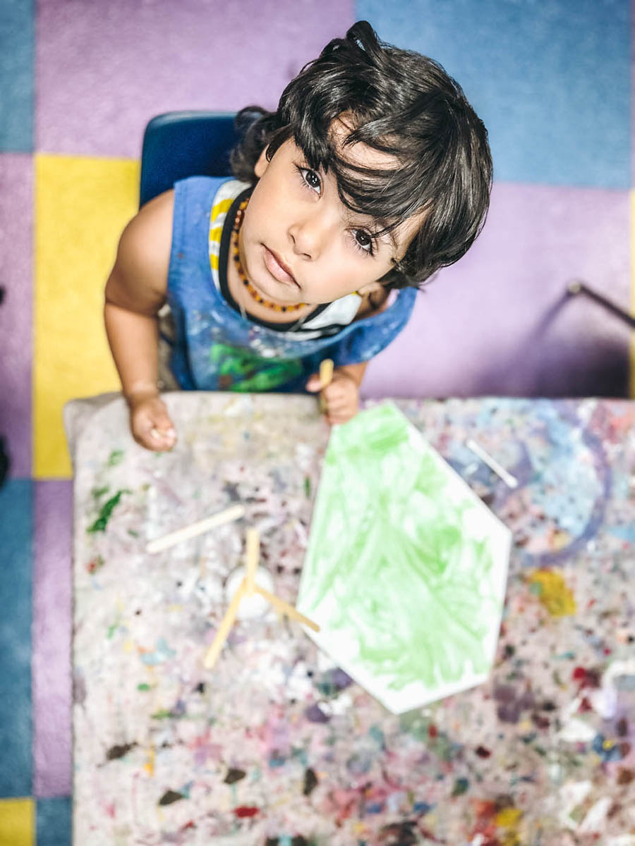 Romp n' Roll Katy little boy looking up at the camera during an art class.